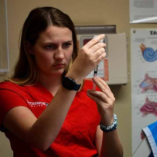 A nursing student fills a syringe